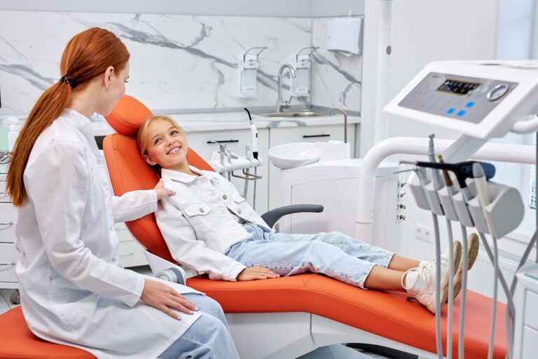 Cute little caucasian child girl in dental surgery waiting on examination couch