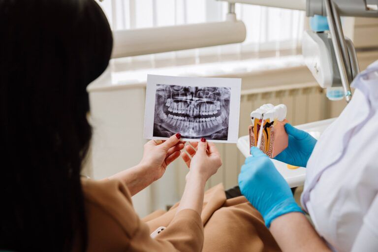 Dentist explains dental Xray and anatomy using a model, promoting oral health education.