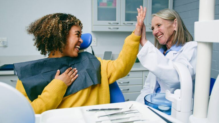 Happy Patient High-Fiving Dentist After a Successful Dental Exam in Office